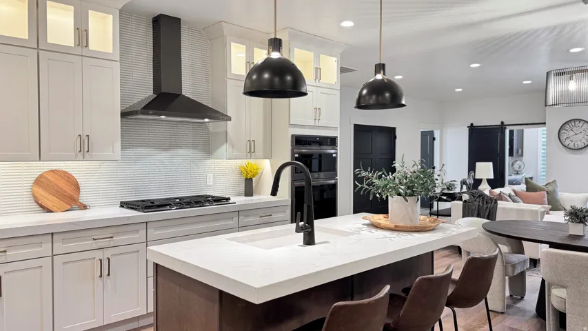 Kitchen featuring a barn door, open floor plan, glass insert cabinets, a breakfast bar area, and light stone counters