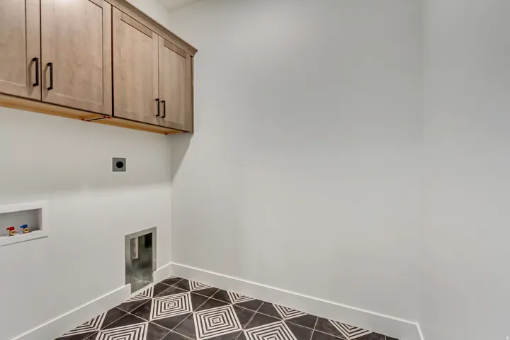 Laundry room featuring dark tile patterned floors, hookup for an electric dryer, cabinet space, and washer hookup