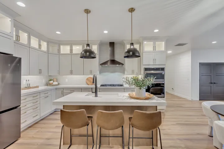 Kitchen featuring glass insert cabinets, stainless steel appliances, light wood-type flooring, white cabinetry, and decorative backsplash