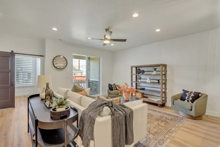 Living room with a barn door, light wood-style flooring, recessed lighting, and a ceiling fan