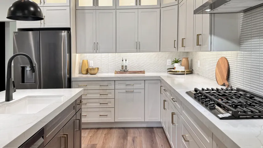 Dual tone kitchen with stainless steel fridge, light stone countertops, dual tone cabinetry, glass fronted cabinets, and black gas cooktop