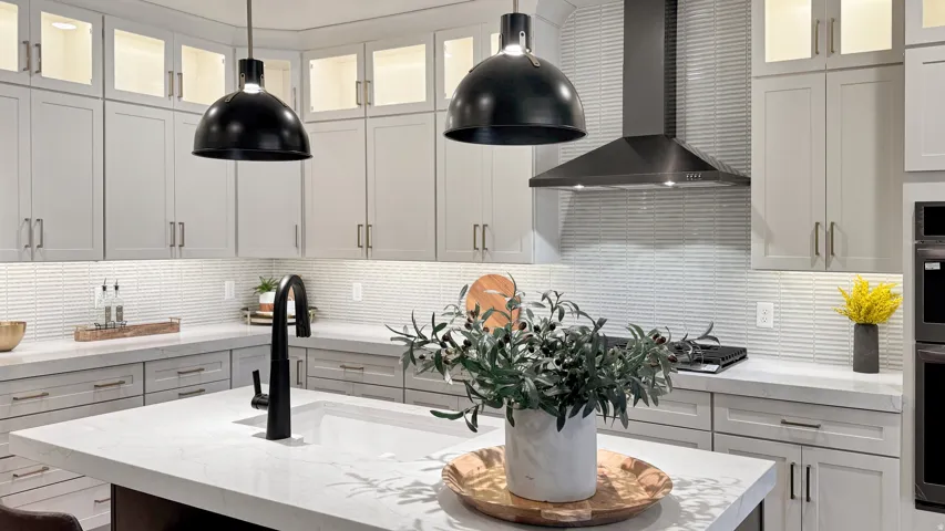 Kitchen featuring tasteful backsplash, glass fronted cabinets, decorative light fixtures, stainless steel appliances, and light stone counters
