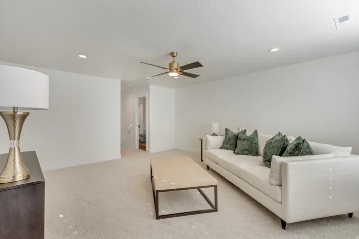 Living area featuring light carpet, a ceiling fan, recessed lighting, and a textured ceiling