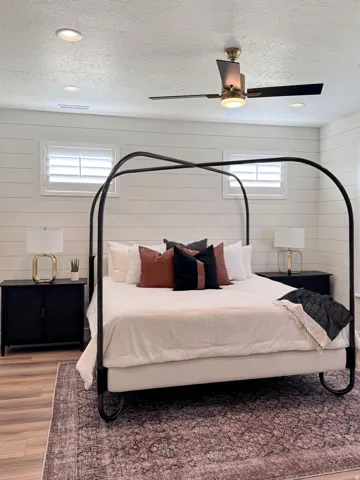 Bedroom with a textured ceiling, wooden walls, wood finished floors, a ceiling fan, and recessed lighting