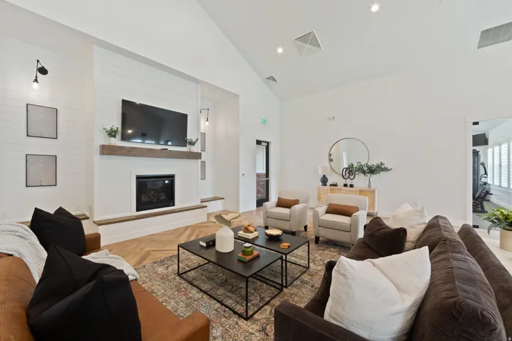 Living room with parquet flooring, lofted ceiling, a large fireplace, and recessed lighting
