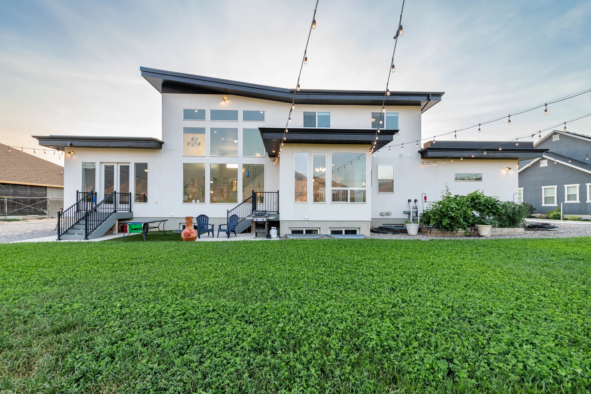 Contemporary exterior with a prominent multi-pane window array, multiple outdoor patios, and a spacious green lawn