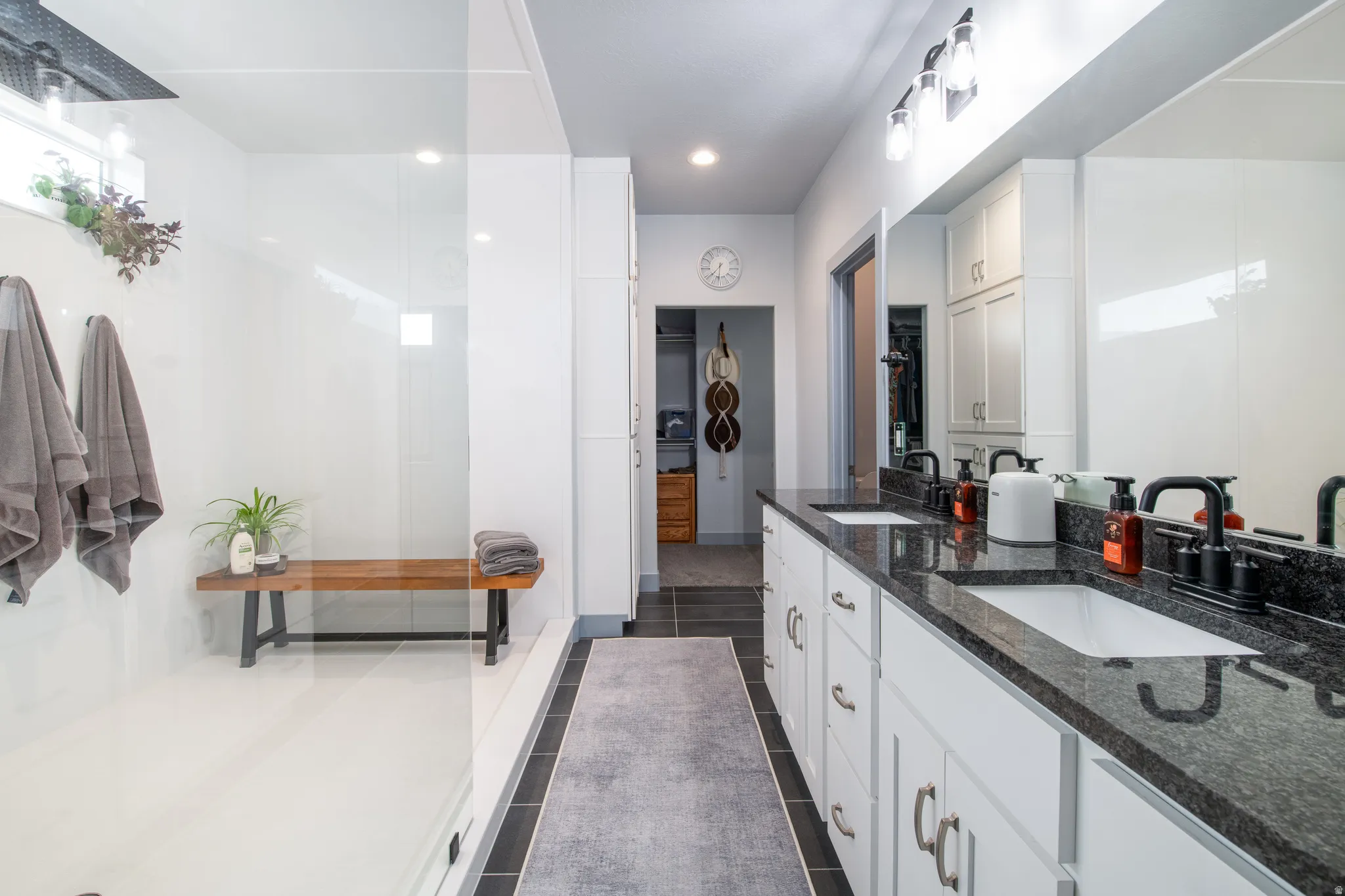 Dual vanity with dark stone countertops, white cabinetry, and matte black fixtures