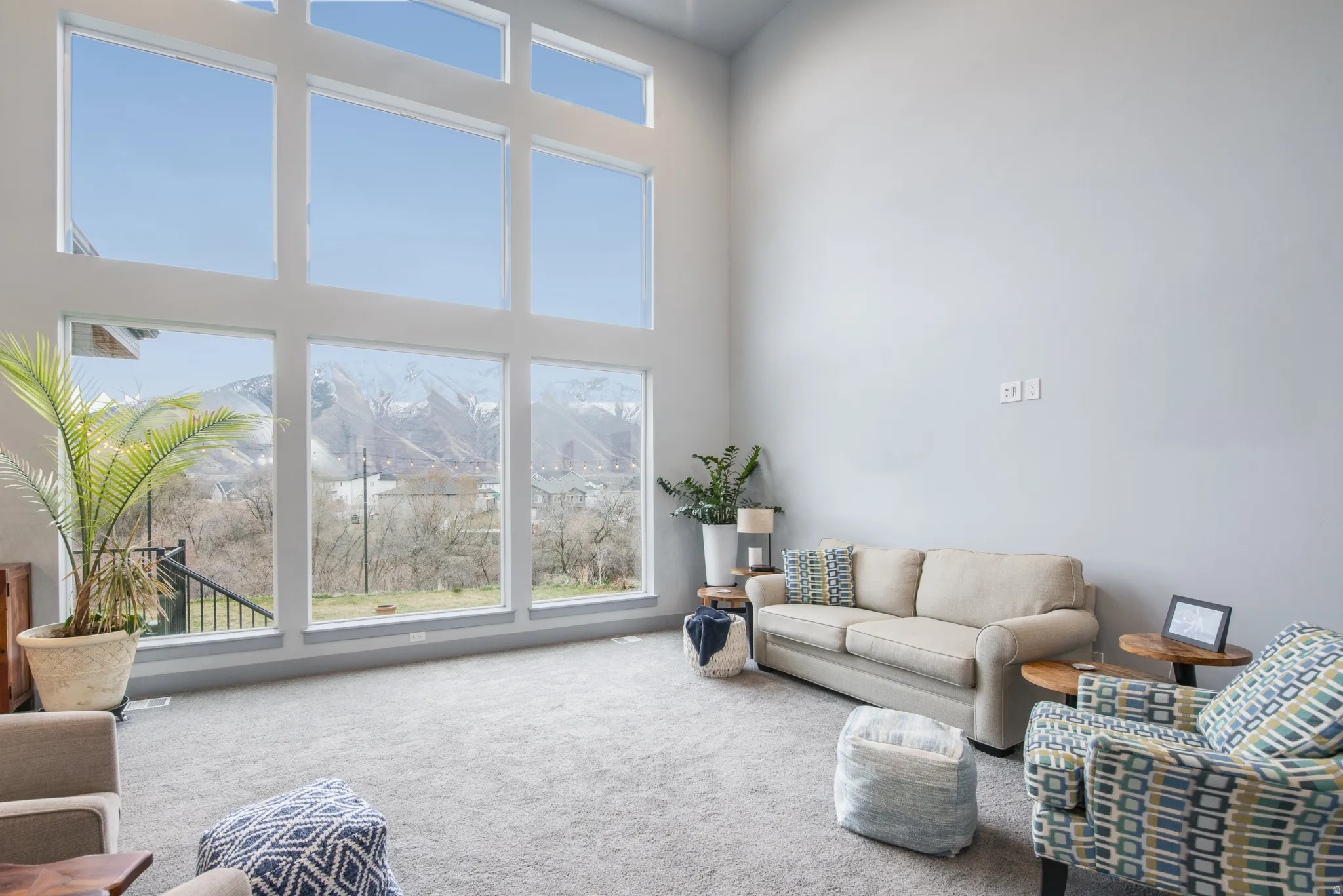 Vaulted ceiling great room with expansive window wall, light gray wall finishes, and gray carpeting