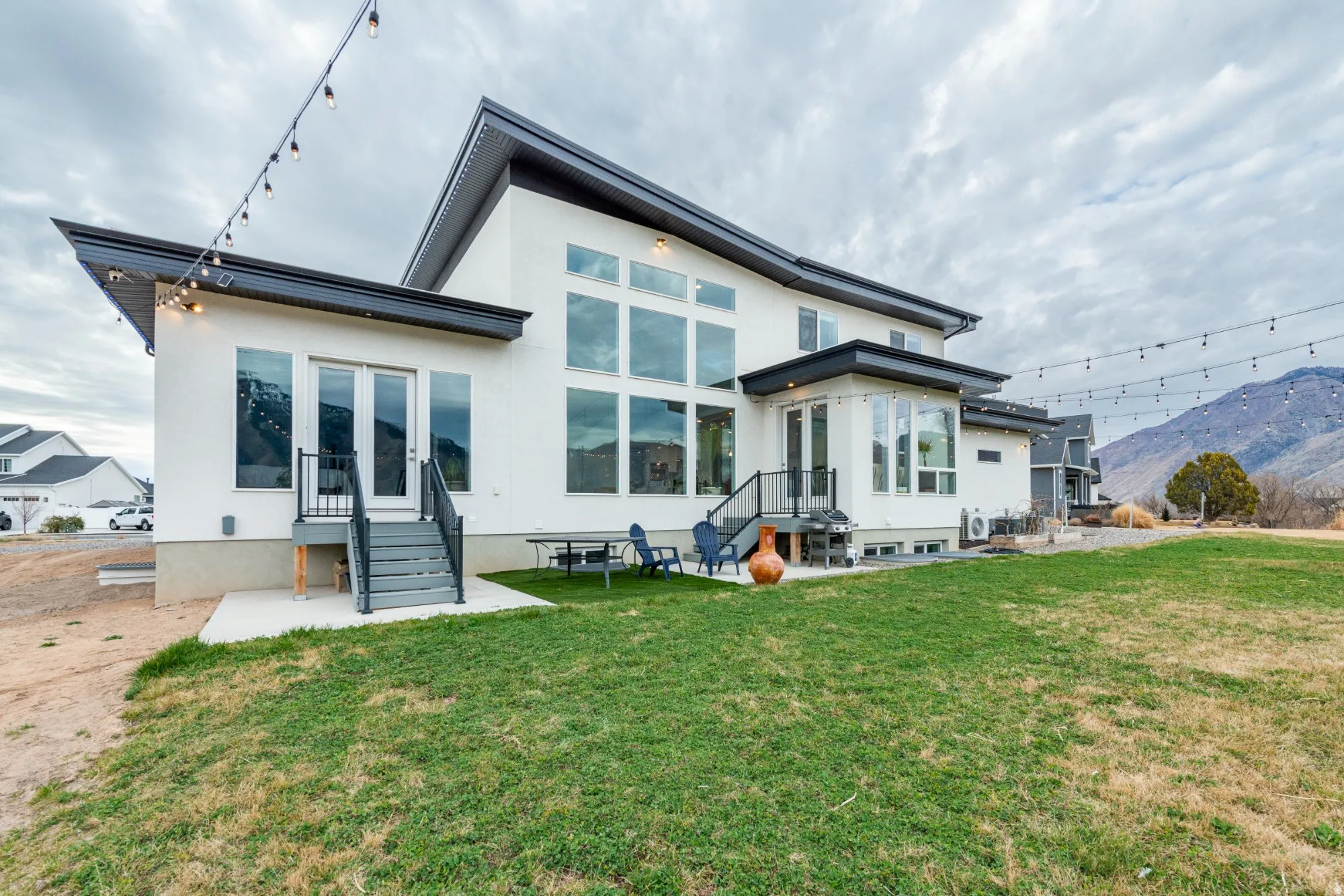 Back of property with a patio area, a yard, stucco siding, and a mountain view