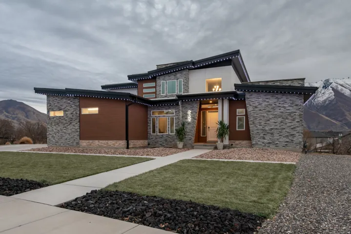 Contemporary home with stone siding, a mountain view, and a front yard