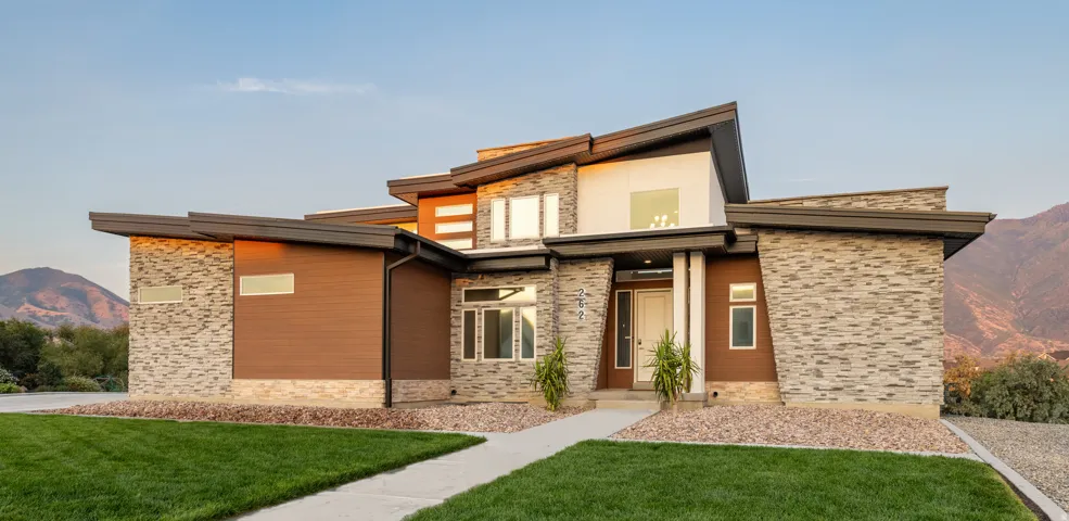 Contemporary facade with stacked stone accents, wood-look siding, and a prominent front entry