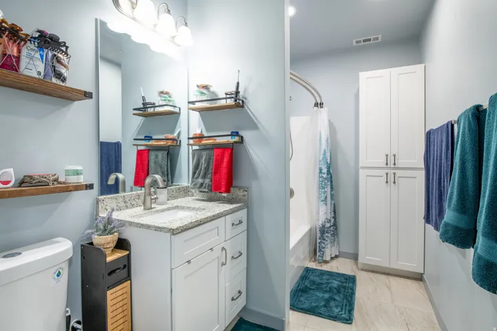Bathroom featuring a white vanity with a granite countertop, undermount sink, and brushed nickel faucet