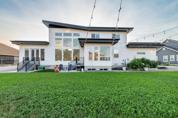 Contemporary exterior with a prominent multi-pane window array, multiple outdoor patios, and a spacious green lawn