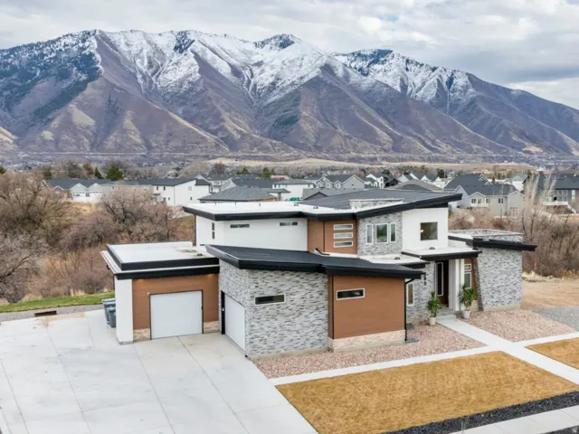 View of front of property with stone siding, a mountain view, a residential view, concrete driveway, and an attached garage