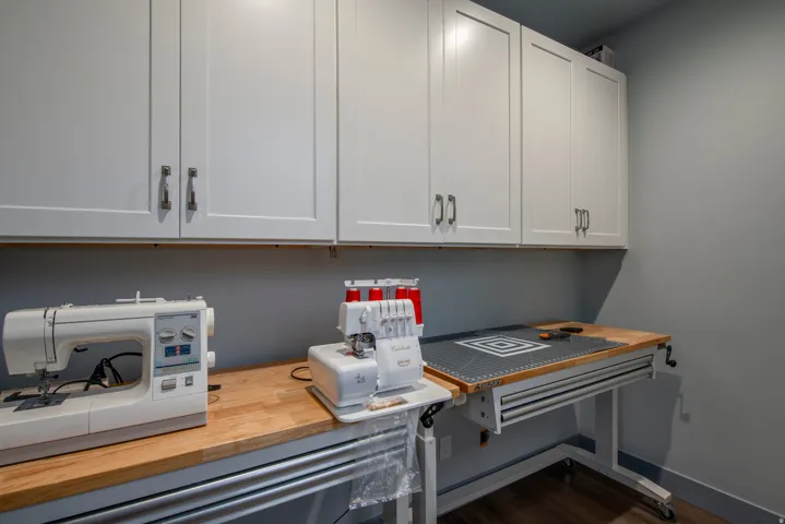 White shaker-style cabinetry with brushed nickel hardware, light wood-finish countertop, and durable wood-finish flooring