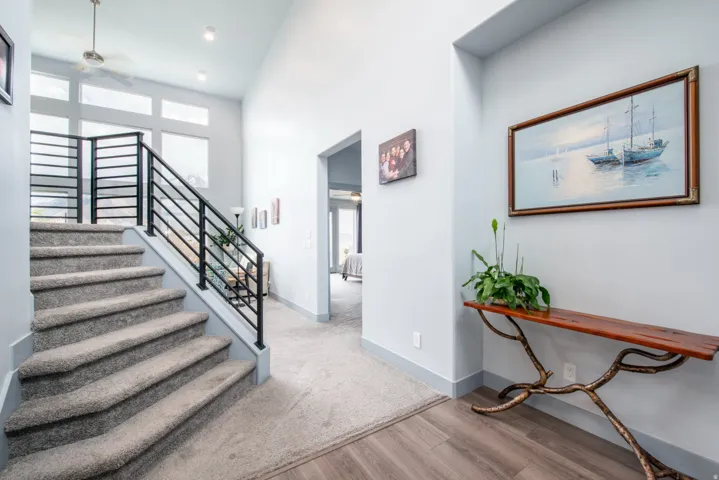 Stairs featuring a ceiling fan, wood finished floors, a high ceiling, and recessed lighting