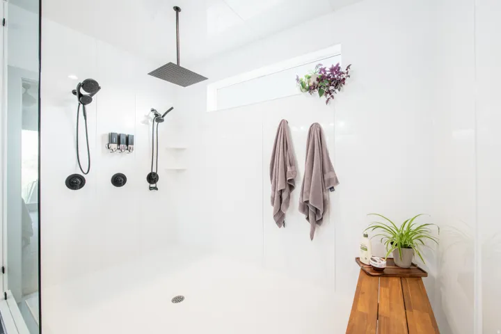 Spacious shower stall with white paneling and a large rain shower head