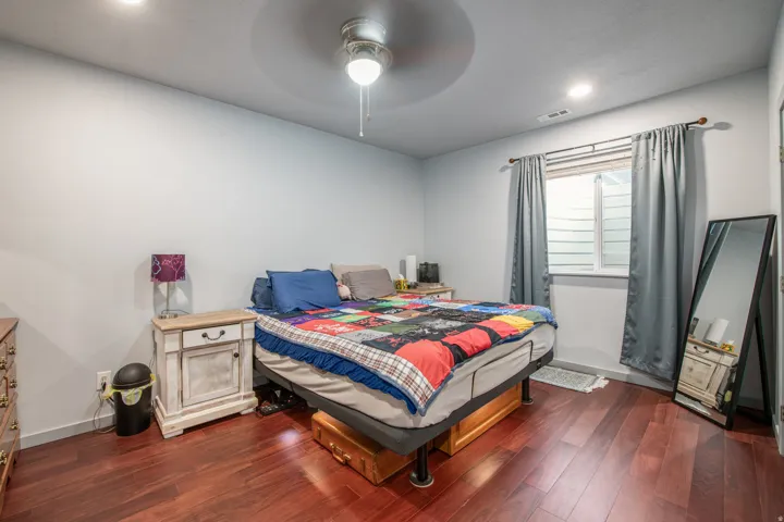 Wood-finish flooring with an overhead ceiling fan and recessed lighting