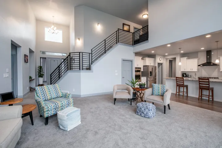 Living area with a high ceiling, hanging lights, and carpet floors