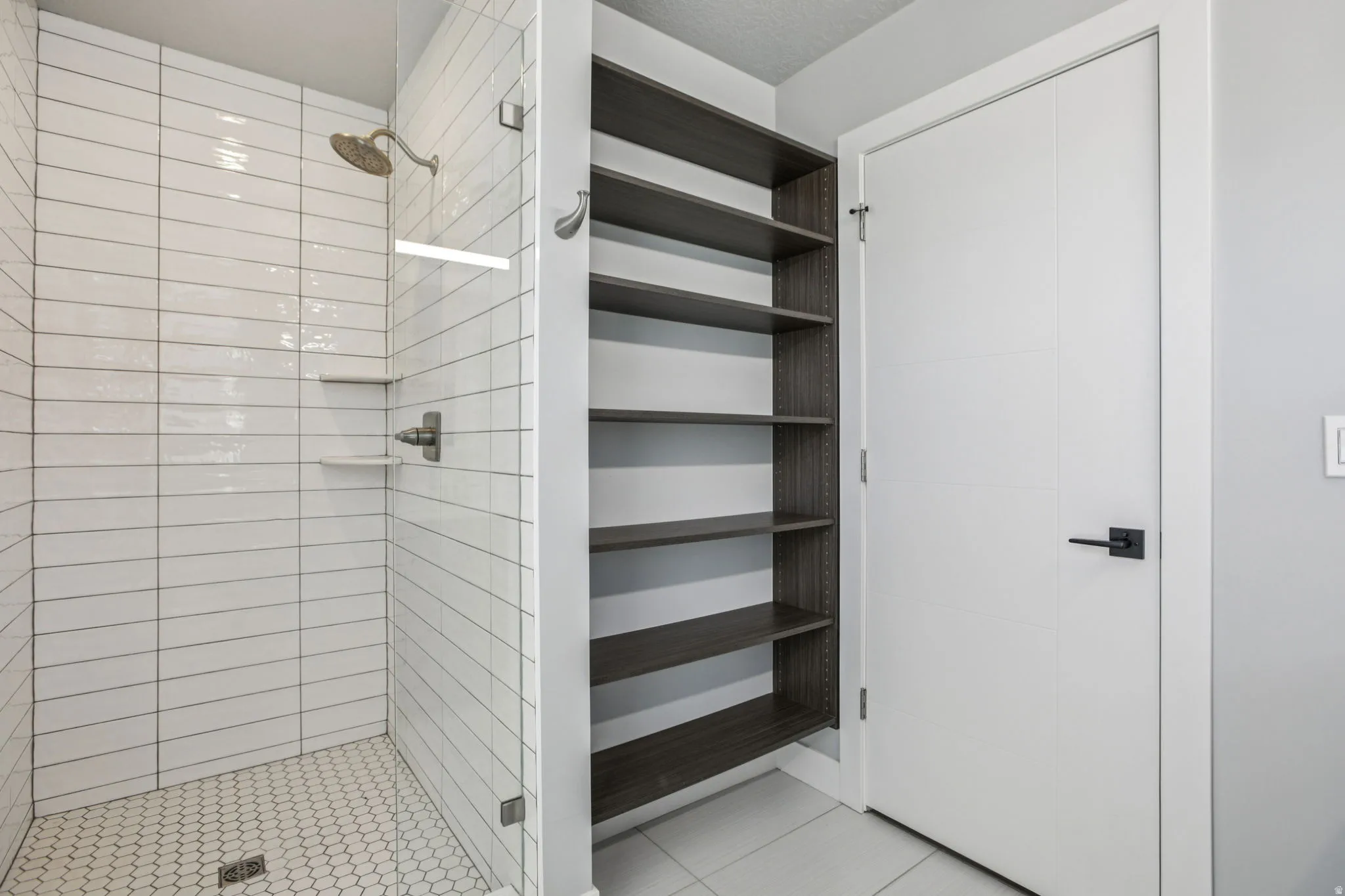 Full bath featuring a shower stall and light tile patterned flooring
