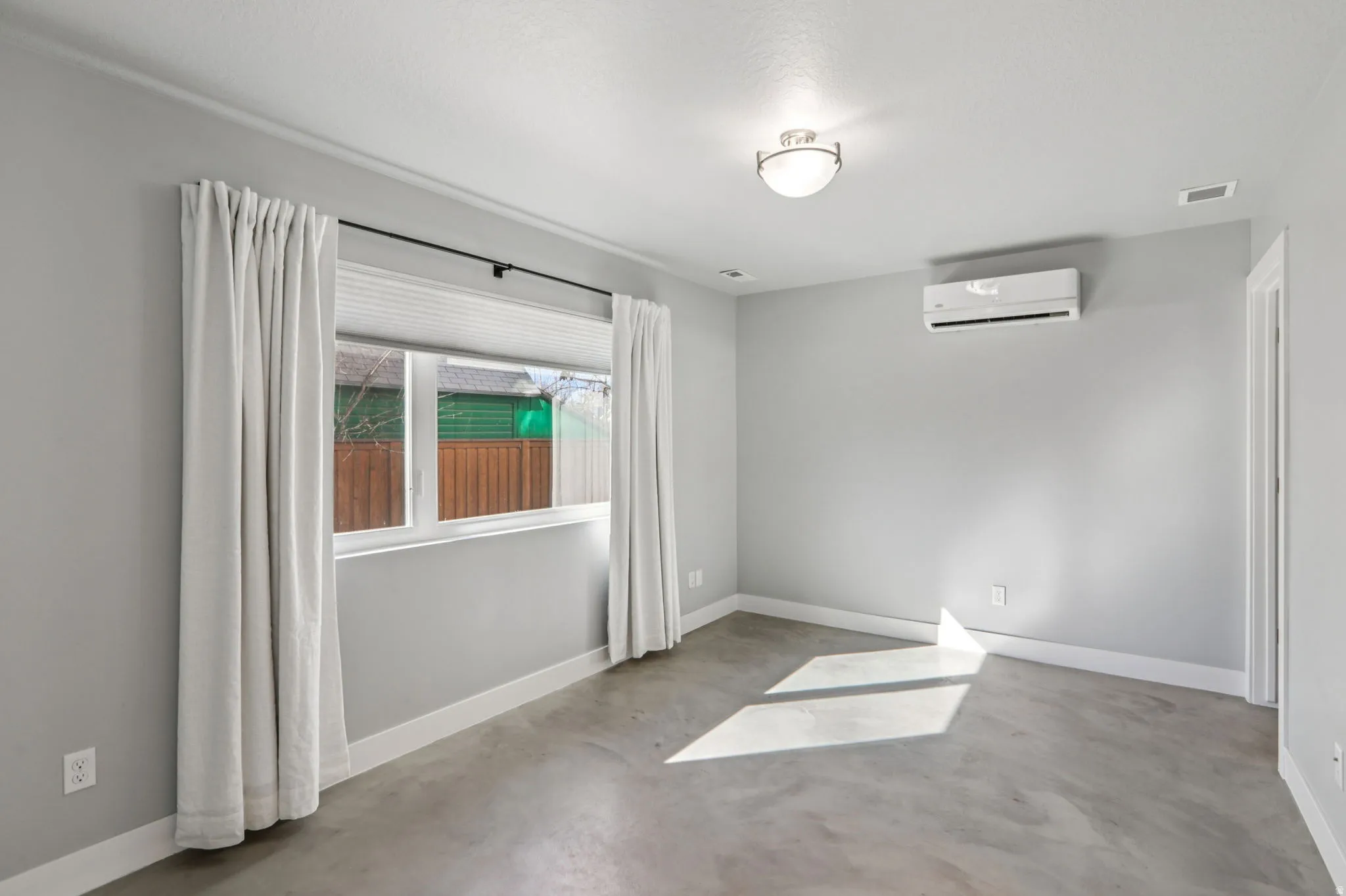 Unfurnished room featuring concrete flooring and a wall mounted mini split