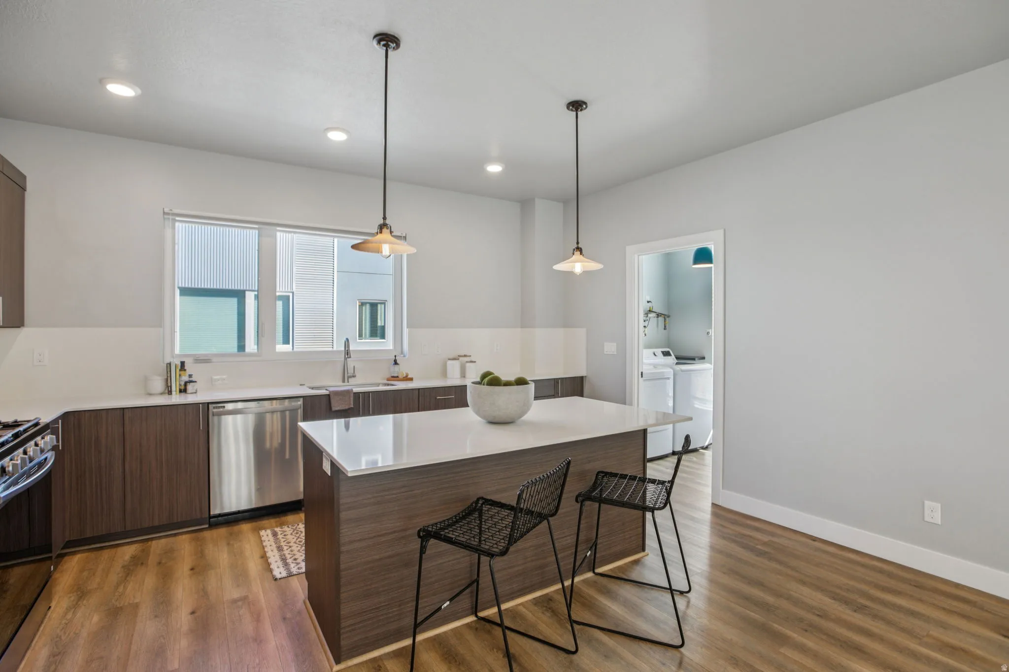 Kitchen featuring a breakfast bar area, modern cabinets, stainless steel appliances, dark wood finish cabinets, and dark wood-style flooring