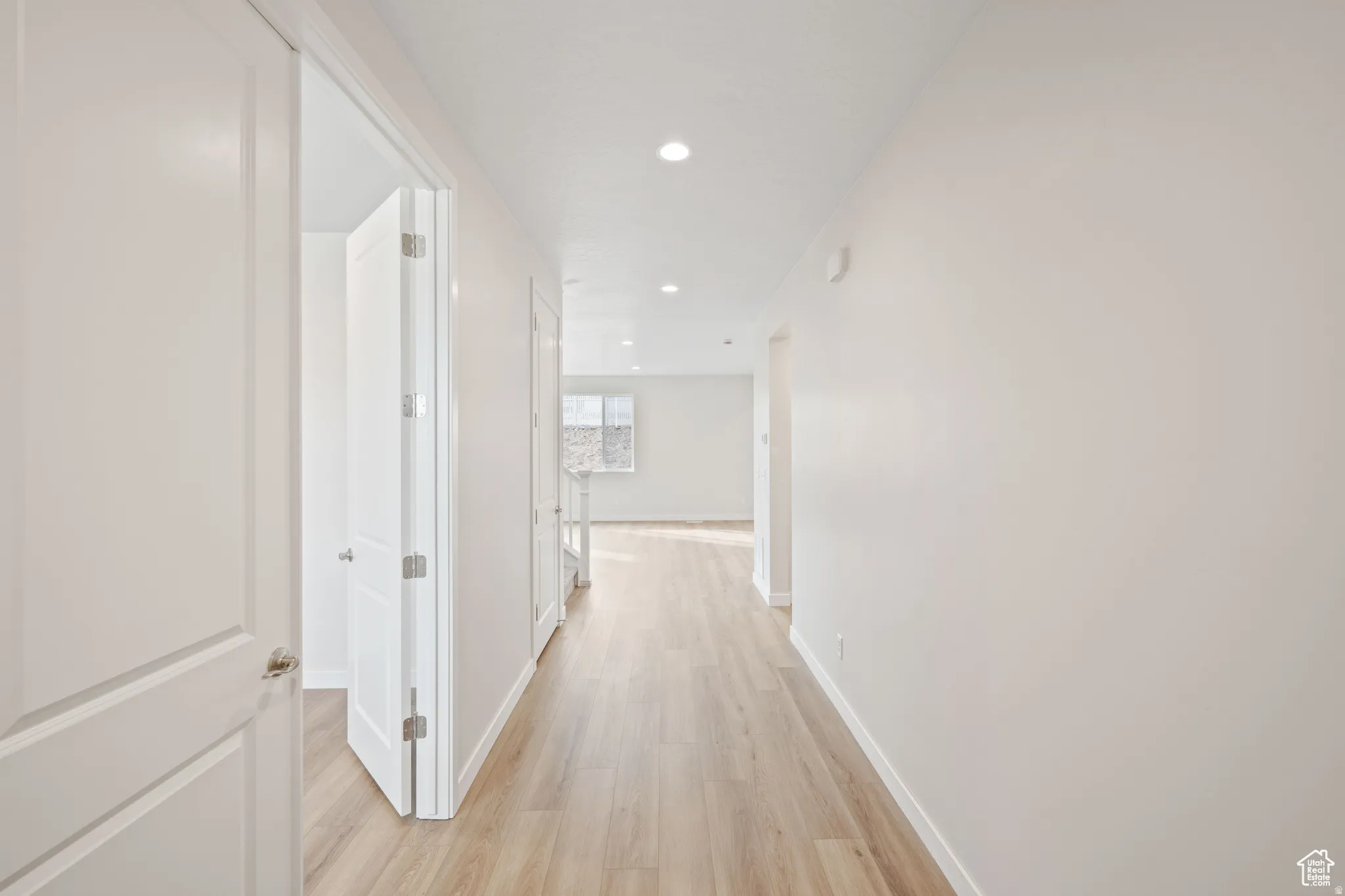 Corridor with light wood-type flooring and recessed lighting