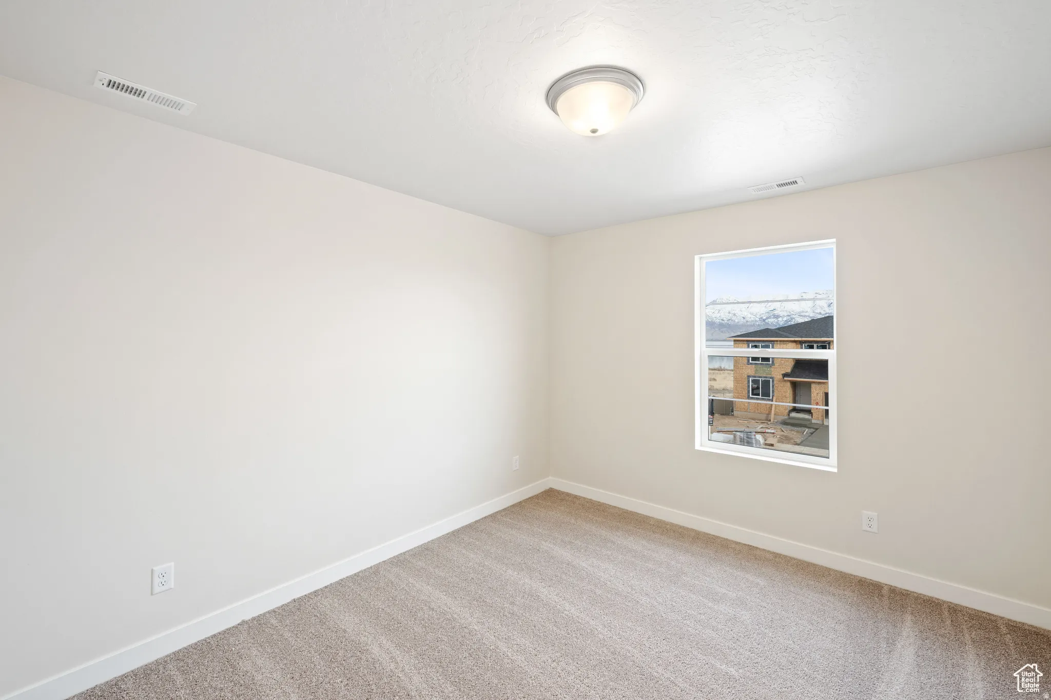 Spare room with baseboards and light colored carpet