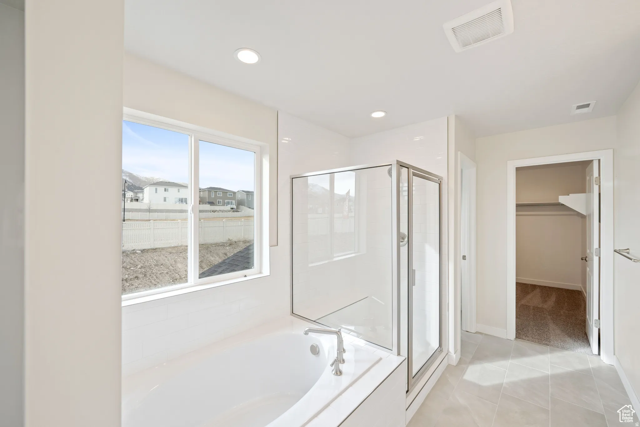 Full bath featuring a spacious closet, a shower stall, a garden tub, light tile patterned flooring, and recessed lighting
