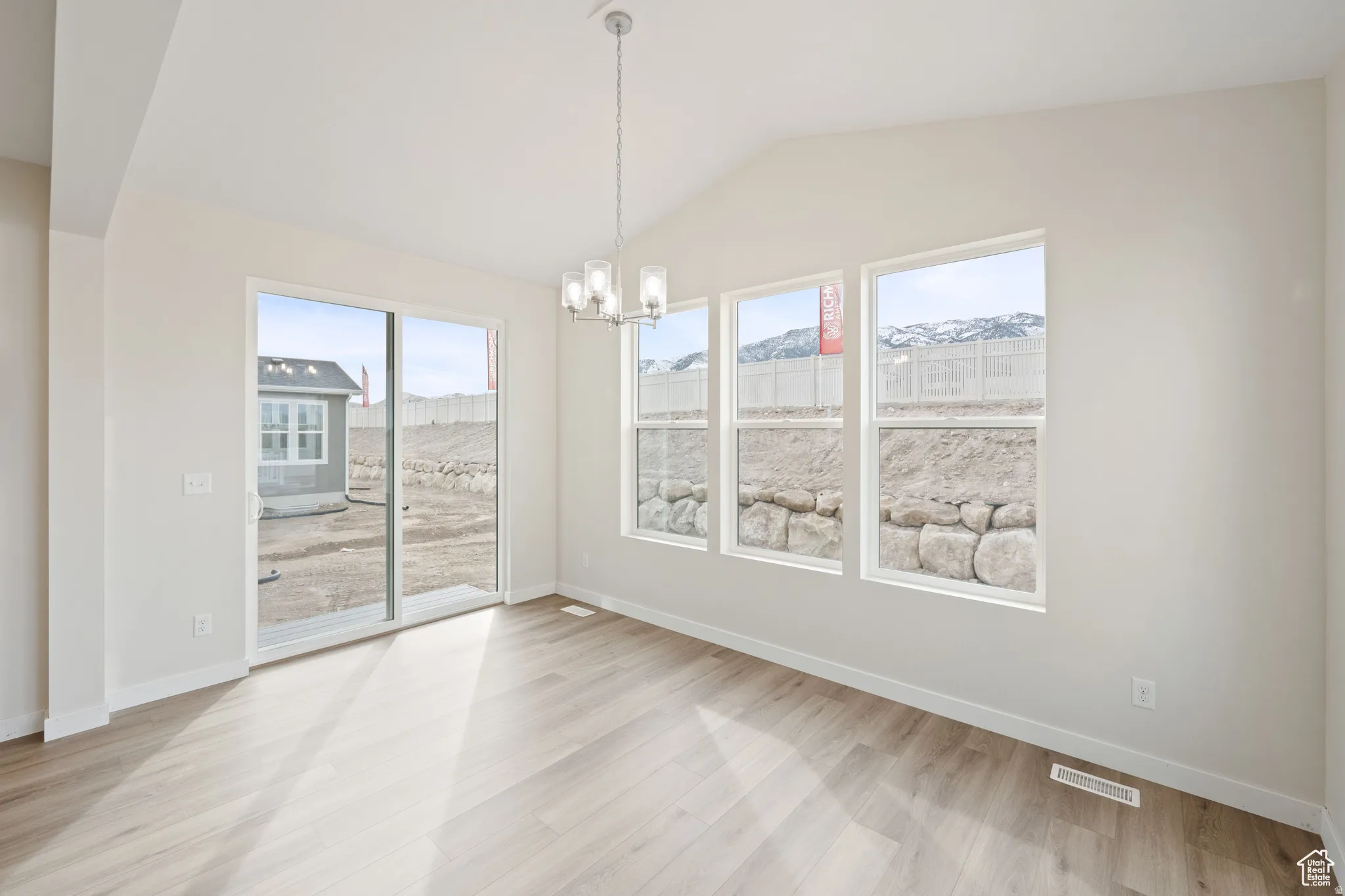 Unfurnished dining area featuring a chandelier, vaulted ceiling, and light wood finished floors