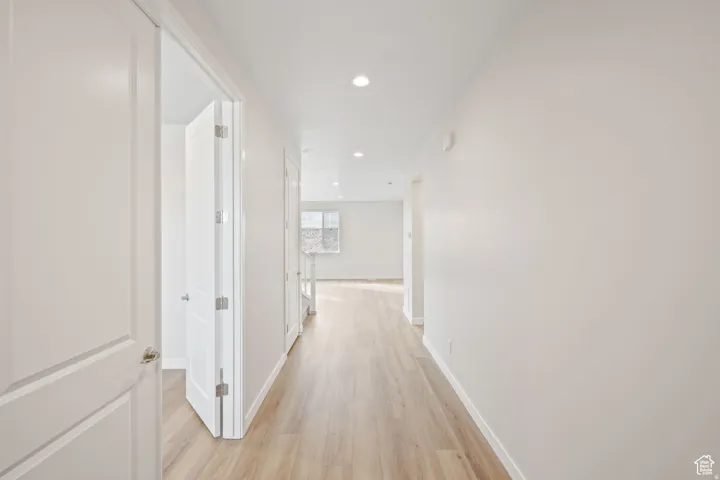 Corridor with light wood-type flooring and recessed lighting