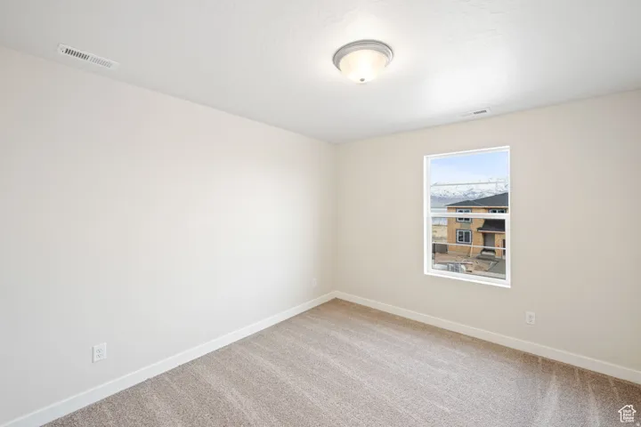 Spare room with baseboards and light colored carpet