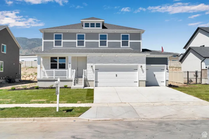 Traditional style home with covered porch, driveway, roof with shingles, an attached garage, and a garage