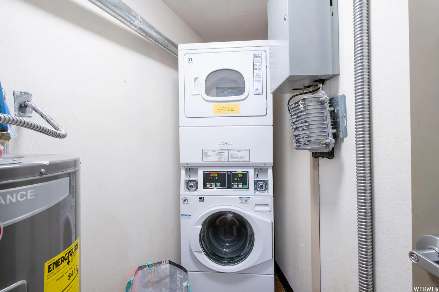 Laundry area with water heater and stacked washer / dryer