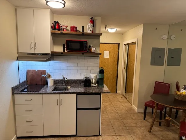 Kitchen featuring stainless steel fridge, electric induction panel,  microwave, decorative backsplash