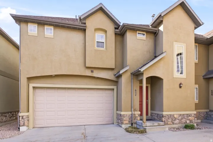 Traditional-style home with stone siding, a garage, stucco siding, and concrete driveway