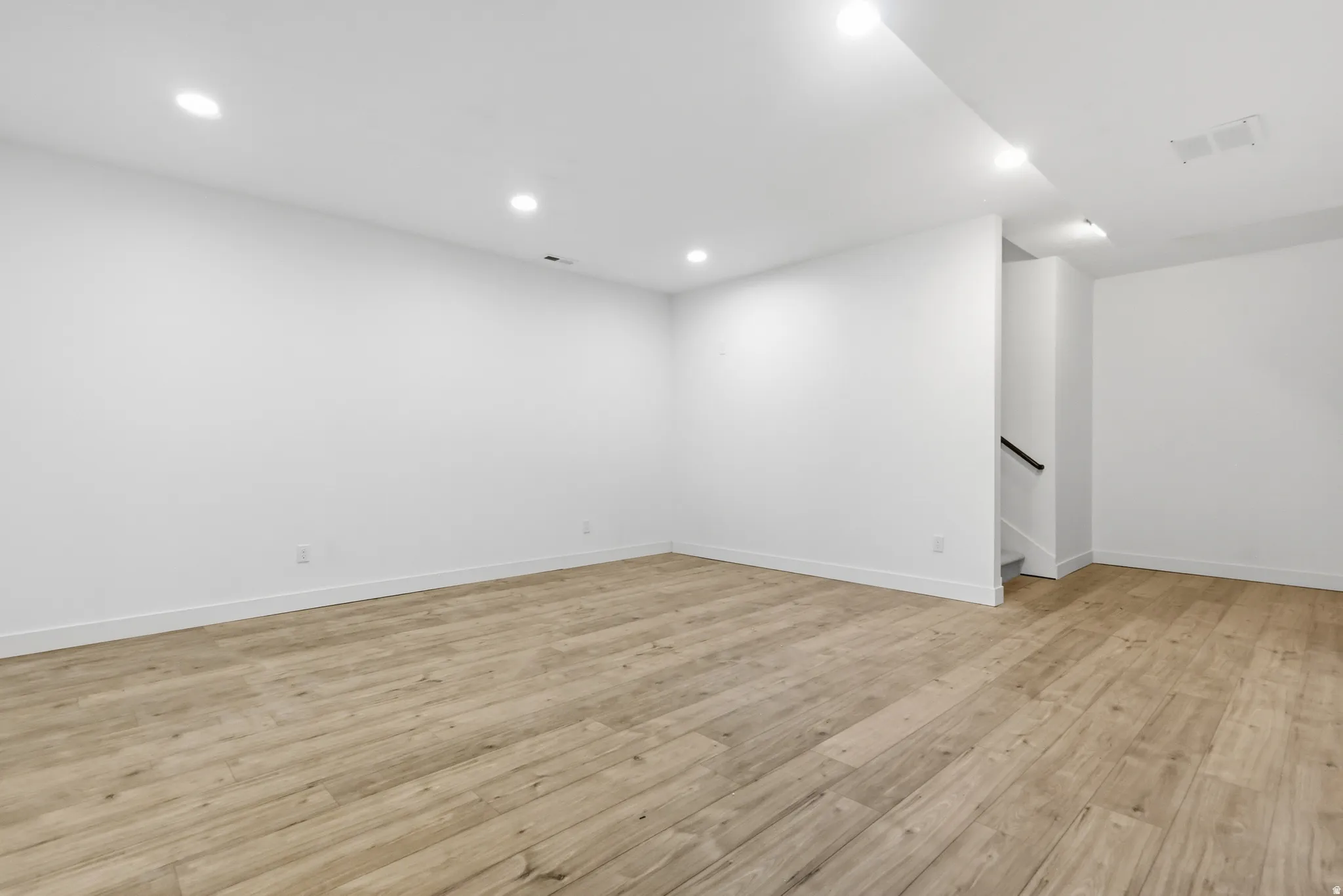 Basement with light wood-style flooring and recessed lighting