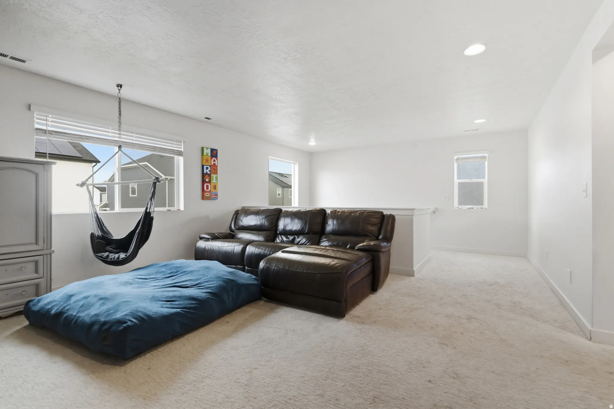 Living area with light carpet and recessed lighting