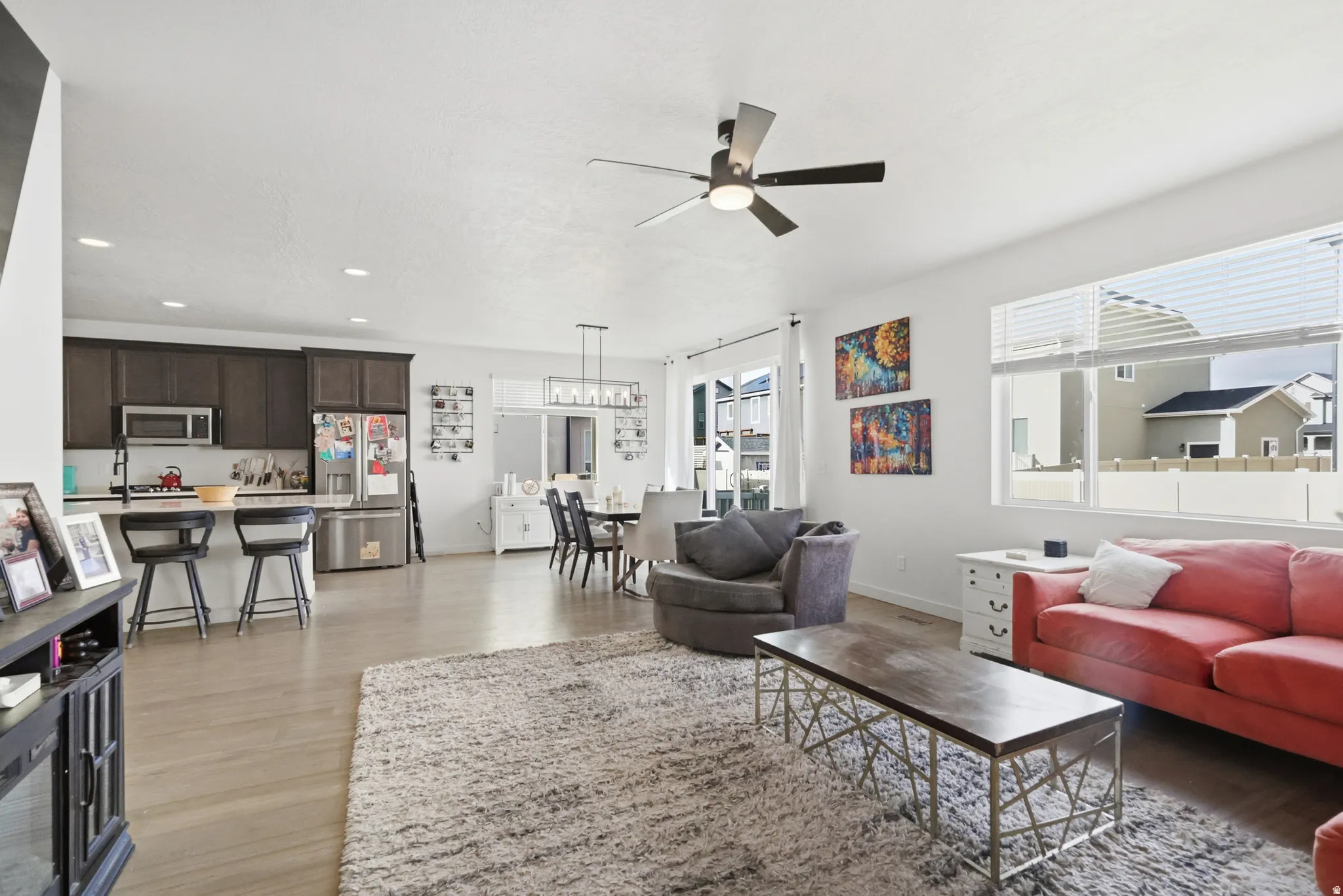 Living room with light wood  floors, ceiling fan, and recessed lighting