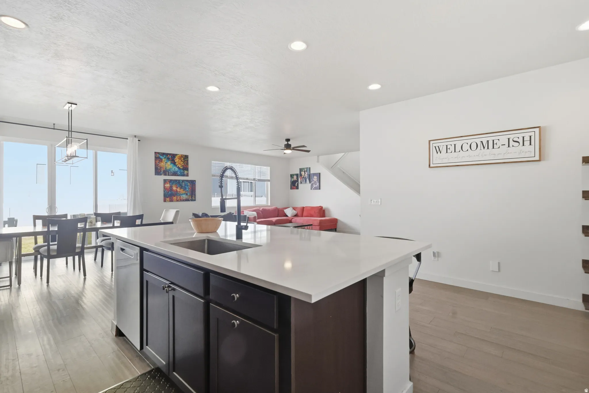 Kitchen with open floor plan, a kitchen island with sink, pendant lighting, light wood floors, and light quartz counters