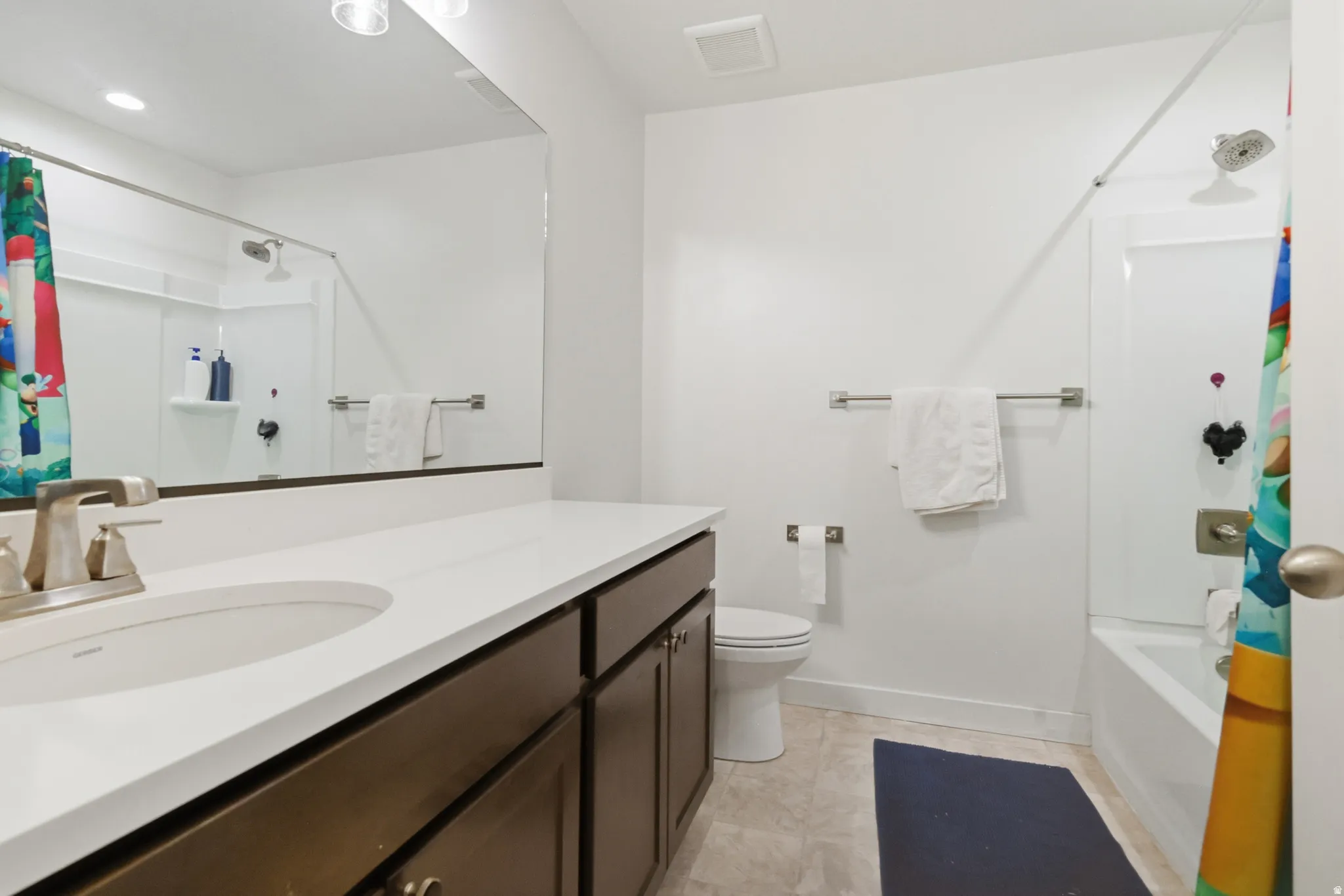 Full guest bathroom with vanity, shower / bathtub combination with curtain, and light tile patterned flooring