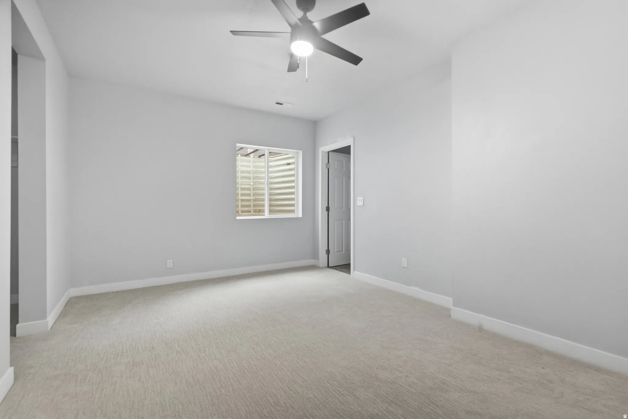 Unfurnished bedroom featuring a ceiling fan and light carpet