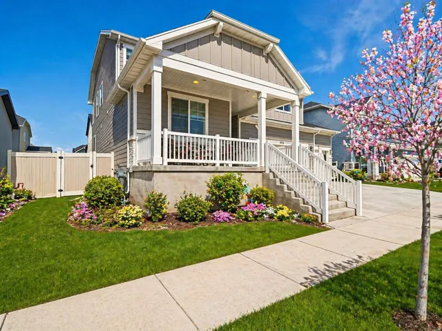 View of front of property with a porch, board and batten siding, a gate, and a front lawn
