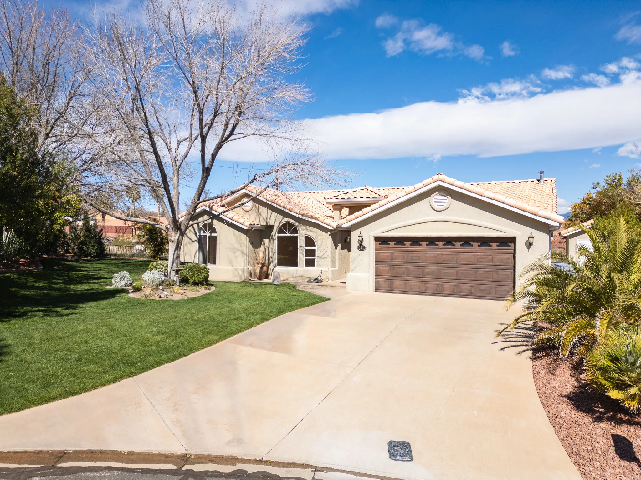 Mediterranean / spanish-style house featuring a garage, concrete driveway, stucco siding, a front yard, and a tiled roof