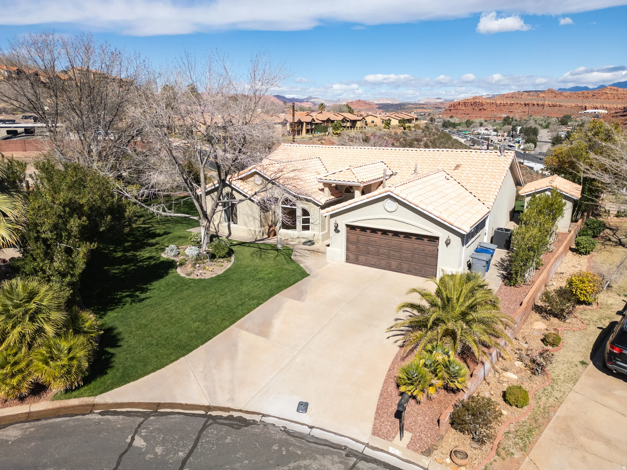 View of front facade with stucco siding, a garage, concrete driveway, a front yard, and a tiled roof