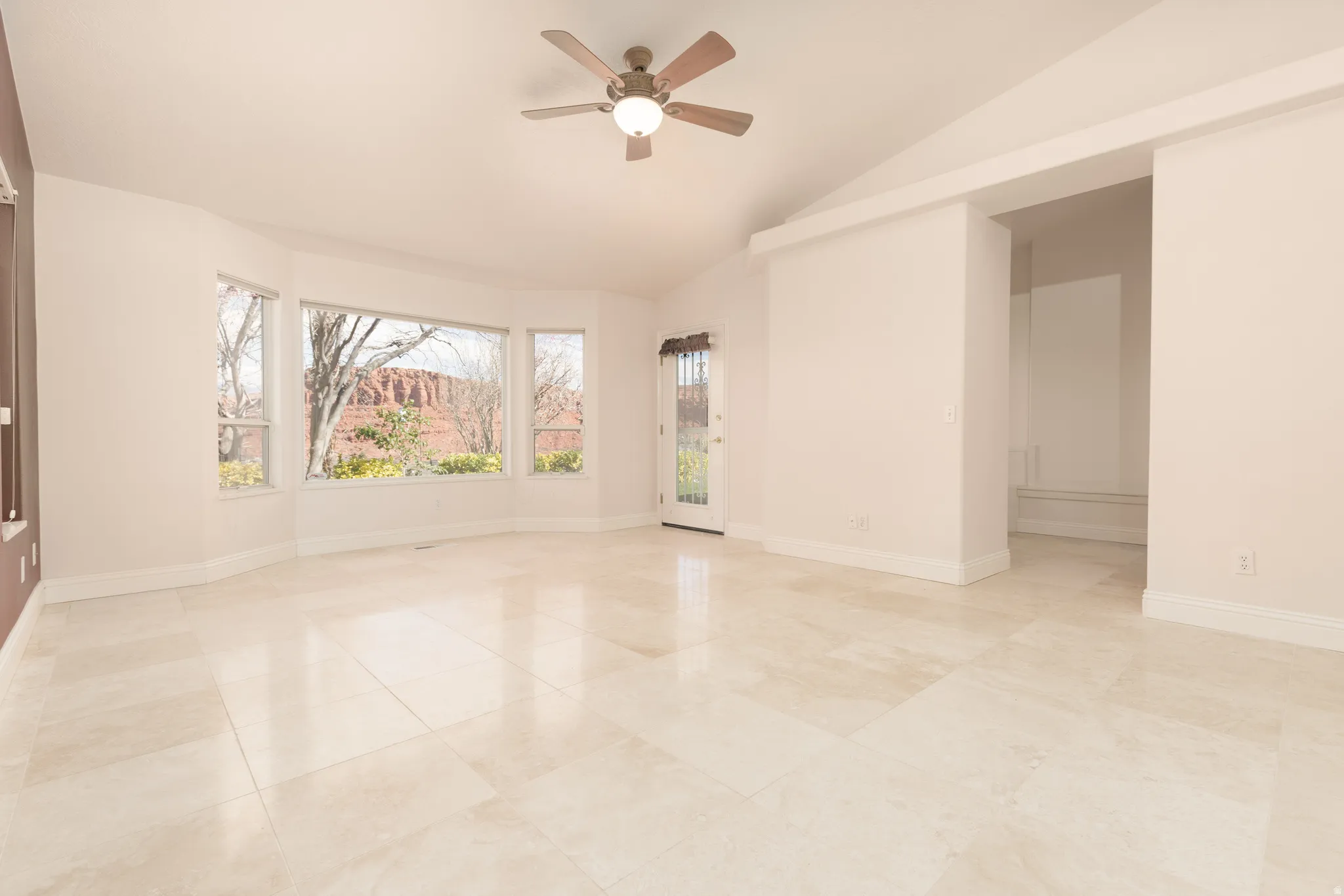 Empty room featuring a ceiling fan and vaulted ceiling