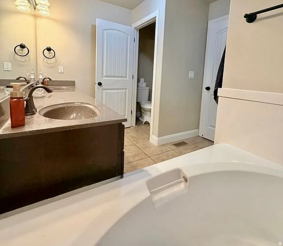 Full bath featuring double vanity and light tile patterned floors