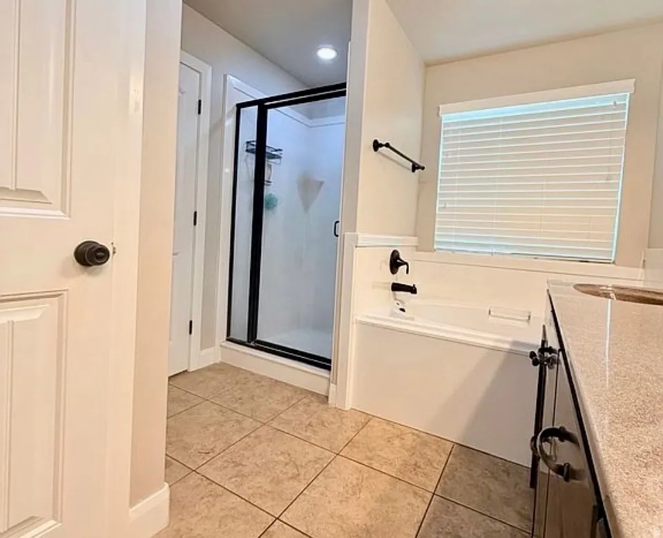 Bathroom featuring vanity, a bath, a shower stall, and light tile patterned floors