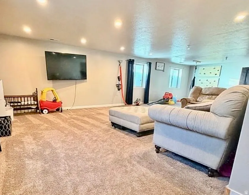 Living area with light carpet and recessed lighting