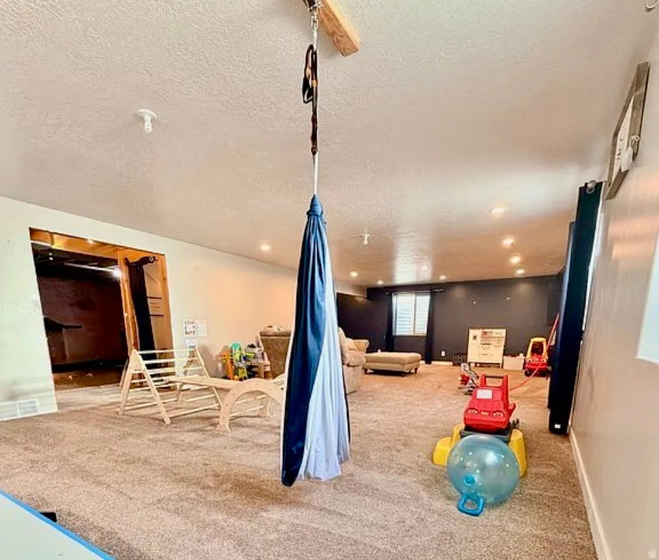 Game room with light colored carpet and a textured ceiling
